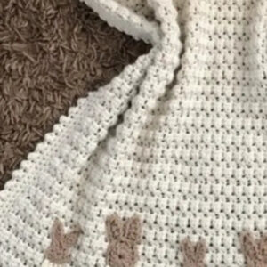 Handmade cream crochet baby blanket with teddy bear details along the border