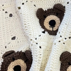 Handmade cream crochet baby blanket with brown teddy bear faces in granny squares